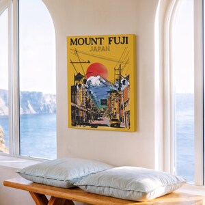 Op de afbeelding: Een ingelijste canvas print met een gele achtergrond, met de tekst "MOUNT FUJI JAPAN". Het kunstwerk toont de berg Fuji, een rode zon en een straatbeeld. De illustratie is een levendige weergave van een Japans landschap.