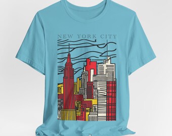 May include: A light blue t-shirt with a graphic print of a stylized cityscape in red, yellow, and black. The text "NEW YORK CITY" is printed above the graphic.