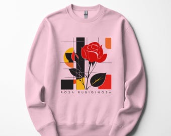 Könnte beinhalten: Hellrosa Sweatshirt mit einer roten Rosenillustration und geometrischen Formen in Schwarz, Gelb und Orange. Der Text "ROSA RUBIGINOSA" ist darunter aufgedruckt. Rundhalsausschnitt.