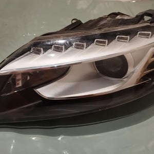 Peut inclure: Un ensemble de phare de voiture avec un boîtier noir et une lentille transparente. Le phare comprend une série de lumières LED et une lentille de projecteur. Le design est moderne et élégant, axé sur la fonctionnalité et l'esthétique.