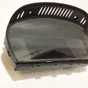 Op de afbeelding: Zwarte kunststof dashboard-instrumentencluster met een transparante kunststof afdekking en een zwart scherm.