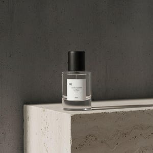 Pu&ograve; includere: Un flacone di profumo in vetro trasparente con tappo nero, etichettato "01" e "changements de l'&acirc;me". Il flacone &egrave; appoggiato su una superficie bianca strutturata contro uno sfondo grigio scuro. La parola "envy" &egrave; stampata in basso sull'etichetta.