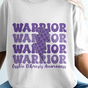Puede incluir: Camiseta blanca con un gráfico de rayo morado y el texto "WARRIOR" repetido cuatro veces. El texto "Cystic Fibrosis Awareness" está impreso debajo del gráfico.
