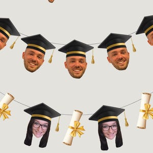 May include: A decorative banner featuring cutouts of faces wearing black and gold graduation caps, interspersed with rolled diploma scrolls tied with gold ribbons. The text "Plus a free cupcake topper!" appears above a single matching face cutout.