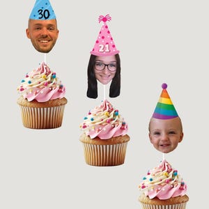 Può includere: Tre cupcake con glassa rosa e zuccherini colorati. Ogni cupcake ha una faccia su uno stecchino con un cappello da festa. I cappelli hanno i numeri 30, 21 e un design arcobaleno.