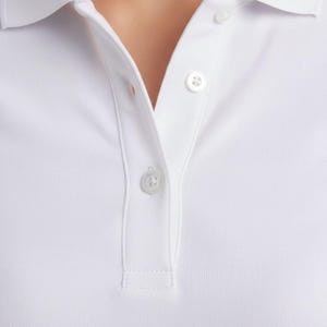 A close-up view of a person wearing a white collared shirt with two white buttons visible.