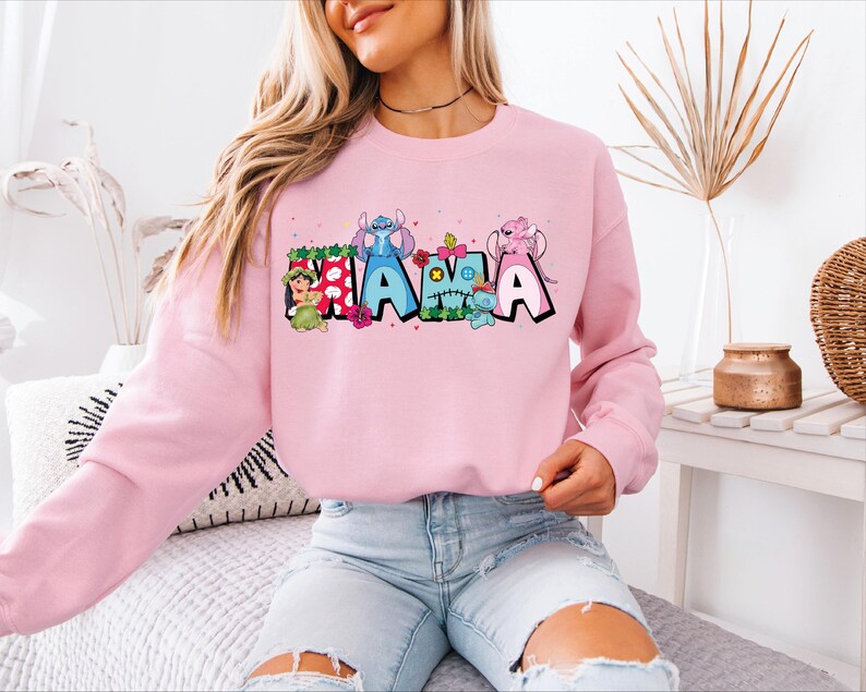 a woman sitting on a bed wearing a pink sweatshirt