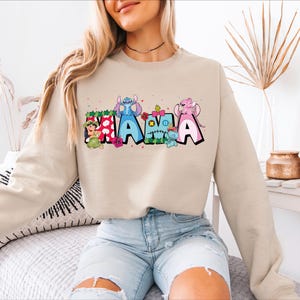 a woman sitting on top of a bed wearing a sweatshirt