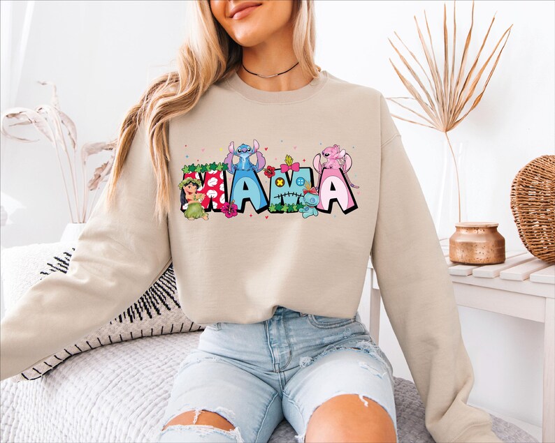 a woman sitting on top of a bed wearing a sweatshirt