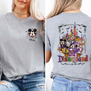A woman wearing a gray t-shirt with a Disney-themed graphic on the back.