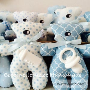Puede incluir: Colecci&oacute;n de ositos de peluche hechos a mano en varias telas estampadas azules y blancas. Cada oso tiene un lazo y un biber&oacute;n o chupete adjunto. Los osos tienen ojos bordados negros y est&aacute;n dise&ntilde;ados para un baby shower o evento similar.