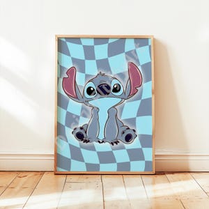 May include: Framed art print featuring a cartoon character with large ears, blue fur, and big eyes. The character is set against a blue and gray checkered background. The artwork is in a wooden frame.