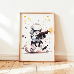 Op de afbeelding: Een ingelijste print met een cartoon Stormtrooper in witte bepantsering, met een zwart blastergeweer. De illustratie bevat gele sterren, rode lijnen en grijze rookeffecten, tegen een witte achtergrond. Het kunstwerk is in een houten lijst.