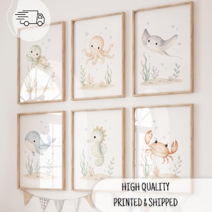 Op de afbeelding: Een set van zes ingelijste wandposters met aquarelillustraties van een zeeschildpad, octopus, rog, walvis, zeepaardje en krab. Elke afbeelding toont een zeedier in een zanderige onderwateromgeving met zeewier en luchtbellen.