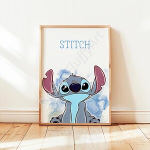 May include: A framed print of the character Stitch from Lilo & Stitch. The artwork shows Stitch in blue and grey, with large eyes and ears. The word "STITCH" is written above the character in blue. The background has blue watercolour-like accents.
