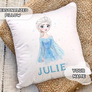 Op de afbeelding: Een wit, gepersonaliseerd kussen met een aquarel-illustratie van Elsa uit Frozen. Het kussen heeft de naam "Julie" en "YOUR NAME" erop gedrukt.