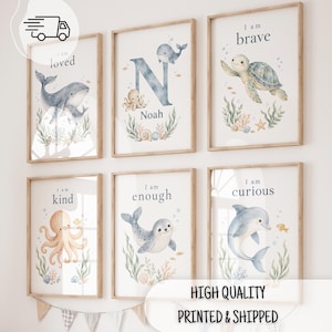 May include: Six framed wall art prints featuring watercolour sea creatures including a whale, octopus, turtle, seal, and dolphin. Each print displays text such as I am loved, I am brave, I am kind, I am enough, I am curious, and the name Noah.