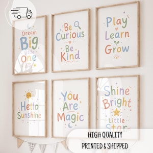Peut inclure: Six cadres muraux en bois clair contenant des affiches avec du texte et des illustrations aux couleurs pastel. Les impressions présentent les phrases Dream Big Little One, Be Curious Be Kind, Play Learn Grow, Hello Sunshine, You Are Magic et Shine Bright Little Star.