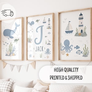 Op de afbeelding: Drie ingelijste wandposters met een nautisch thema, voorzien van illustraties van een walvis, octopus, schildpad, zeilboot en vuurtoren. De middelste poster toont de letter J en de naam JACK in blauwe letters op een witte achtergrond.