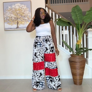 Puede incluir: Pantalones palazzo de pernera ancha con un estampado abstracto en blanco y negro y paneles de encaje rojo. Los pantalones se combinan con una camiseta sin mangas blanca. Adecuado para ocasiones informales o semiformales.