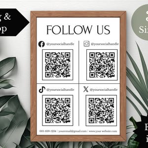 May include: A framed print with the words "FOLLOW US" and social media icons with QR codes. The print includes the text "Drag & Drop", "3 Sizes", and "Extra icons". The frame is brown.