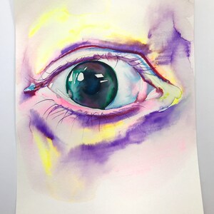 May include: A close-up watercolor painting of a human eye. The eye is green with a black pupil and is surrounded by pink and purple watercolor washes.
