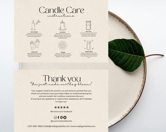 May include: Two cream-colored cards with candle care instructions and a thank you message. The cards are on a beige plate with a green leaf. The text includes instructions on trimming the wick, letting it burn, and safety precautions.