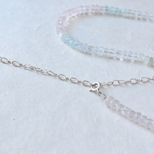 Pu&ograve; includere: Una collana delicata con una catena d'argento e un gradiente di perline rosa chiaro e blu chiaro.