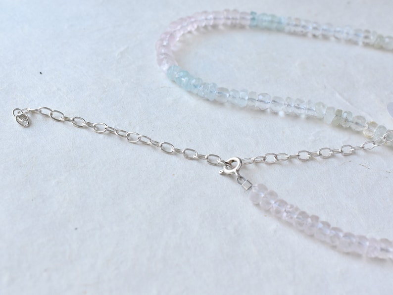 Pu&ograve; includere: Una collana delicata con una catena d'argento e un gradiente di perline rosa chiaro e blu chiaro.