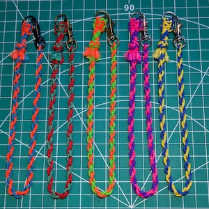May include: Six colorful braided lanyards with metal clasps. The lanyards are in various color combinations: orange and blue, red and green, green and orange, pink and purple, and yellow and blue. Each lanyard is approximately 12 inches long.