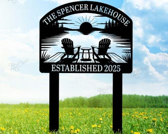 May include: Black metal yard sign with the text "The Spencer Lakehouse Established 2025". The sign depicts a lake scene with two chairs on a dock, a sunset, and trees.