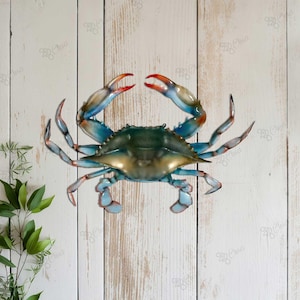 May include: A blue crab with red claws and a light blue and white shell. The crab is on a white wooden background.