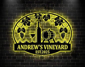 May include: A black metal sign with a yellow neon outline, featuring a wine bottle, glass, and barrel. The sign reads "ANDREW'S VINEYARD EST.2025" and includes grape vines. The background is a dark brick wall.