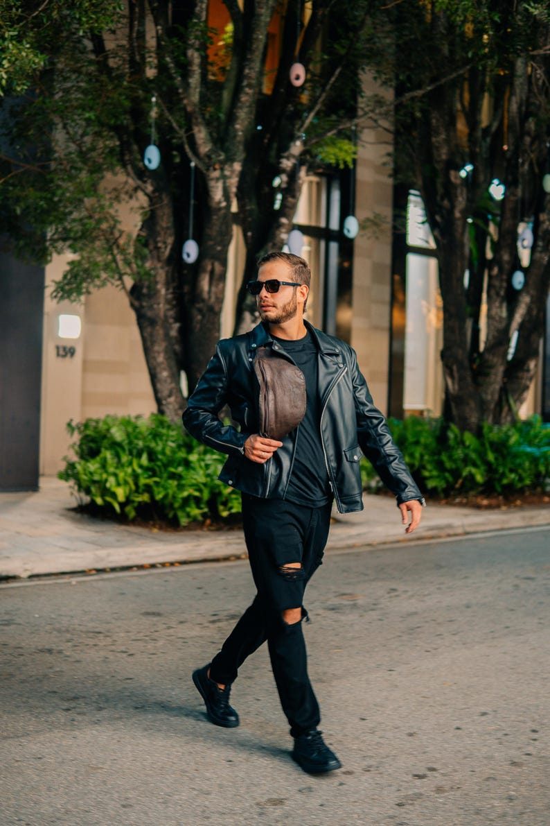 A man wearing the leather side bag as a shoulder bag, paired with a black outfit. Perfect as a fanny pack, a gift for him or her.