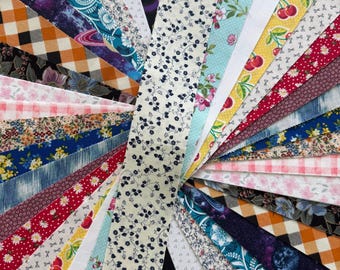 Puede incluir: Abanico de tiras de tela variadas con diversos patrones y colores. Los diseños incluyen motivos florales, cuadros y abstractos en tonos azules, rojos, amarillos y blancos. Las tiras de tela están dispuestas en un patrón radial.