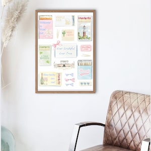 May include: A framed watercolor print featuring various matchbox designs with text like "Welcome to West Lot" and "Ever Grateful Ever True." The artwork includes images of a lighthouse, cactus, and champagne glasses. The frame is brown.