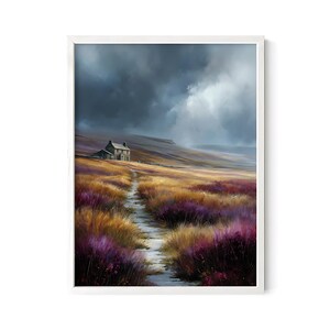 May include: A framed landscape painting depicts a stone cottage on a hillside, with a path leading through fields of purple and gold wildflowers. The sky is filled with dramatic, dark clouds, creating a moody atmosphere. The artwork is set in a white frame.