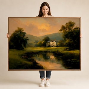 May include: A rectangular framed landscape painting featuring a large manor house situated in a grassy field beside a calm river. The scene includes lush green trees, rolling hills in the distance, and a warm, golden sunset sky with soft clouds.