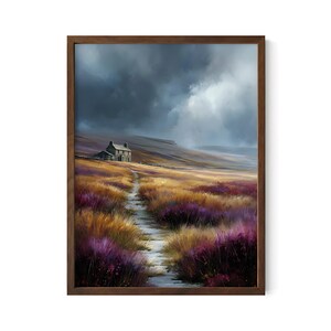 May include: A framed landscape painting depicts a stone cottage on a hillside path. The artwork features a field of purple and gold grasses under a dramatic, cloudy sky. The wooden frame adds a rustic touch to the artwork.