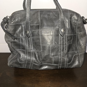 Bolso tipo cartera de piel de color gris con diseño de patchwork, correas cruzadas y asa superior