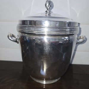 May include: A silver ice bucket with a lid and two handles. The lid has a decorative knob on top.