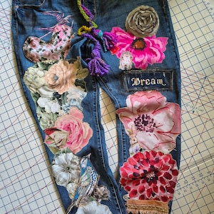 Calça jeans patchwork reciclada com apliques, tamanho 14 a 16, corte reto, elastano, tom médio-escuro, estilo vintage desgastado, boho: apliques artesanais em jeans pintados à mão.