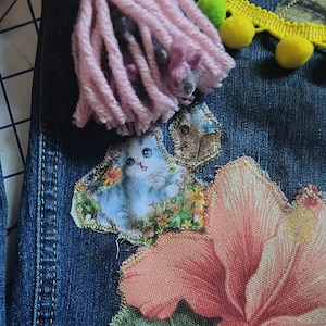 Patchwork Boho AppliquePatched Upcycled Cropped DarkerDenim Cuffed or Straight Jeans SIZE 14 TO 16 Stretch VintageStyledenim.   Inseam 26.  Vintage-look handpainted throughout Flowers, Birds, Cat, and appliques of various designs.  Handmade and handcrafted.   Unique Applique Jeans Distressed.  Highrise High Waisted, Handpainted Handmade Appliqued Straight Style Jeans. Size 14 to 16 depending on your measurements.  Check the measurements.  Handmade Boho Sash Bohemian design crocheted with bells.
