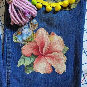 Patchwork Boho AppliquePatched Upcycled Cropped DarkerDenim Cuffed or Straight Jeans SIZE 14 TO 16 Stretch VintageStyledenim.   Inseam 26.  Vintage-look handpainted throughout Flowers, Birds, Cat, and appliques of various designs.  Handmade and handcrafted.   Unique Applique Jeans Distressed.  Highrise High Waisted, Handpainted Handmade Appliqued Straight Style Jeans. Size 14 to 16 depending on your measurements.  Check the measurements.  Handmade Boho Sash Bohemian design crocheted with bells.