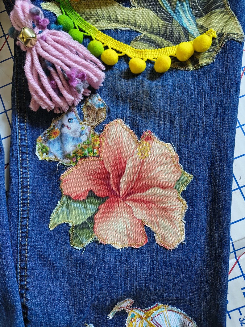 Patchwork Boho AppliquePatched Upcycled Cropped DarkerDenim Cuffed or Straight Jeans SIZE 14 TO 16 Stretch VintageStyledenim.   Inseam 26.  Vintage-look handpainted throughout Flowers, Birds, Cat, and appliques of various designs.  Handmade and handcrafted.   Unique Applique Jeans Distressed.  Highrise High Waisted, Handpainted Handmade Appliqued Straight Style Jeans. Size 14 to 16 depending on your measurements.  Check the measurements.  Handmade Boho Sash Bohemian design crocheted with bells.