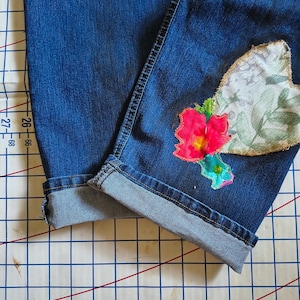 Patchwork Boho AppliquePatched Upcycled Cropped DarkerDenim Cuffed or Straight Jeans SIZE 14 TO 16 Stretch VintageStyledenim.   Inseam 26.  Vintage-look handpainted throughout Flowers, Birds, Cat, and appliques of various designs.  Handmade and handcrafted.   Unique Applique Jeans Distressed.  Highrise High Waisted, Handpainted Handmade Appliqued Straight Style Jeans. Size 14 to 16 depending on your measurements.  Check the measurements.  Handmade Boho Sash Bohemian design crocheted with bells.