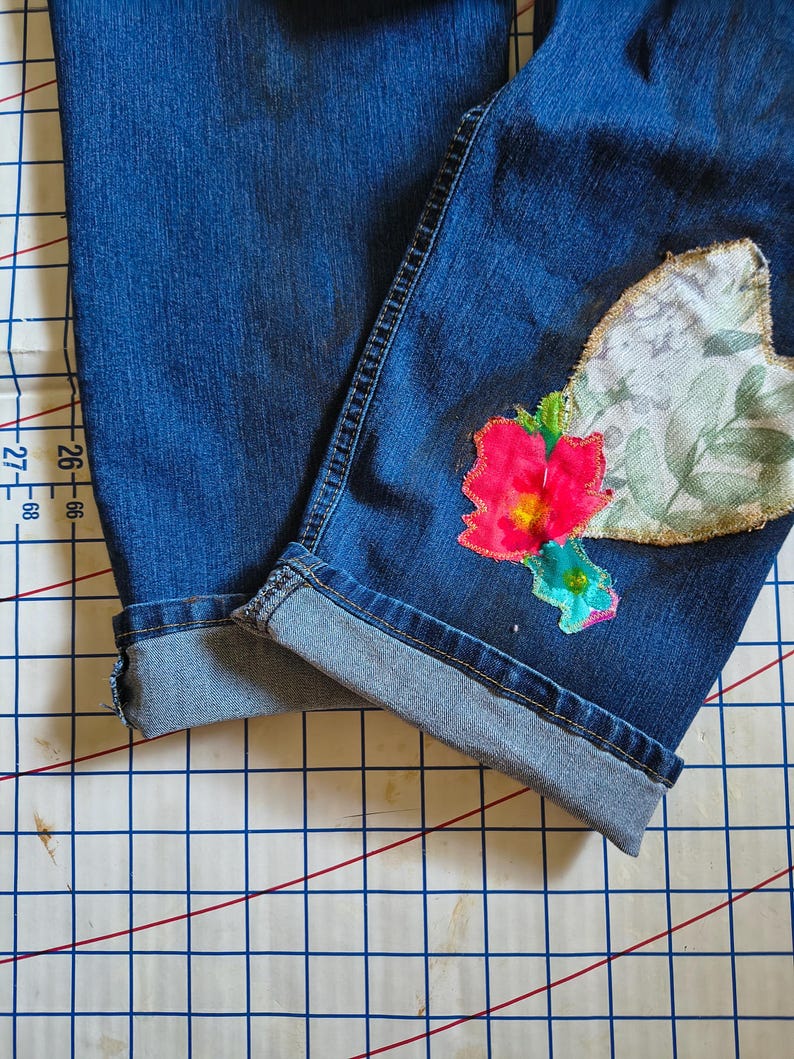 Patchwork Boho AppliquePatched Upcycled Cropped DarkerDenim Cuffed or Straight Jeans SIZE 14 TO 16 Stretch VintageStyledenim.   Inseam 26.  Vintage-look handpainted throughout Flowers, Birds, Cat, and appliques of various designs.  Handmade and handcrafted.   Unique Applique Jeans Distressed.  Highrise High Waisted, Handpainted Handmade Appliqued Straight Style Jeans. Size 14 to 16 depending on your measurements.  Check the measurements.  Handmade Boho Sash Bohemian design crocheted with bells.