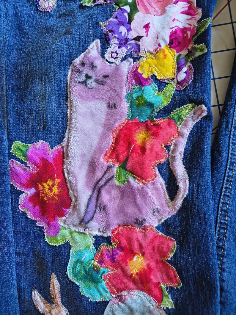 Patchwork Boho AppliquePatched Upcycled Cropped DarkerDenim Cuffed or Straight Jeans SIZE 14 TO 16 Stretch VintageStyledenim.   Inseam 26.  Vintage-look handpainted throughout Flowers, Birds, Cat, and appliques of various designs.  Handmade and handcrafted.   Unique Applique Jeans Distressed.  Highrise High Waisted, Handpainted Handmade Appliqued Straight Style Jeans. Size 14 to 16 depending on your measurements.  Check the measurements.  Handmade Boho Sash Bohemian design crocheted with bells.