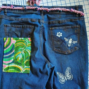 Patchwork Boho AppliquePatched Upcycled Cropped DarkerDenim Cuffed or Straight Jeans SIZE 14 TO 16 Stretch VintageStyledenim.   Inseam 26.  Vintage-look handpainted throughout Flowers, Birds, Cat, and appliques of various designs.  Handmade and handcrafted.   Unique Applique Jeans Distressed.  Highrise High Waisted, Handpainted Handmade Appliqued Straight Style Jeans. Size 14 to 16 depending on your measurements.  Check the measurements.  Handmade Boho Sash Bohemian design crocheted with bells.