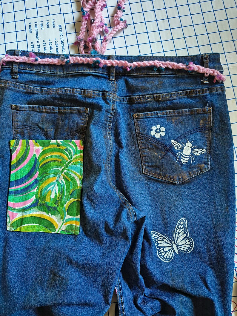 Patchwork Boho AppliquePatched Upcycled Cropped DarkerDenim Cuffed or Straight Jeans SIZE 14 TO 16 Stretch VintageStyledenim.   Inseam 26.  Vintage-look handpainted throughout Flowers, Birds, Cat, and appliques of various designs.  Handmade and handcrafted.   Unique Applique Jeans Distressed.  Highrise High Waisted, Handpainted Handmade Appliqued Straight Style Jeans. Size 14 to 16 depending on your measurements.  Check the measurements.  Handmade Boho Sash Bohemian design crocheted with bells.